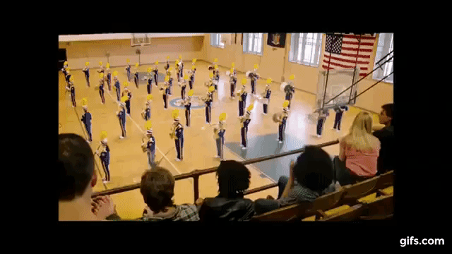 Gif from a video taken from a camera phone of someone in the stands watching the band in the sports hall, all of a sudden band members start to get dusted and people in the stands do to; the camera jerks around at different dusted people